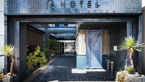 A hotel entrance with a tiled facade, a banner with the hotel name, and potted plants. - R Hotel Nagoya Station (Nagoya)