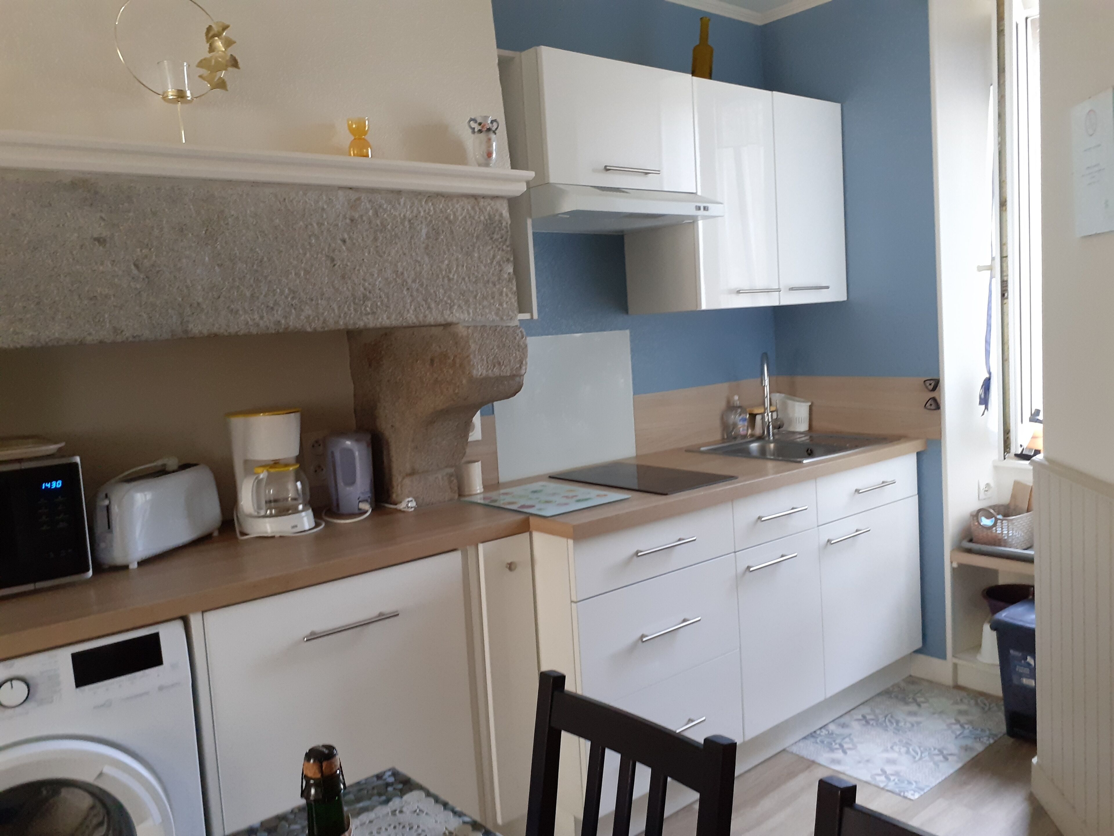 Cocina compacta equipada con lavadora, tostadora, cafetera y un lavamanos pequeño.