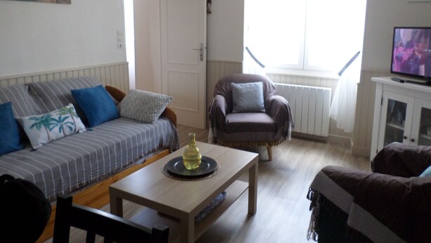 Een woonkamer met een bank, fauteuil, salontafel en een televisie.