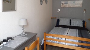 Een slaapkamer met een bed, nachtkastje, lamp en een wanddecoratie.