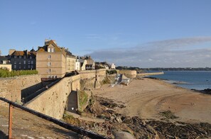 A coastal town with historic stone buildings, a fortified wall, and a sandy beach. - Appartement séjour, cuisine, 1 chambre dans le magnifique quartier de Saint-Malo (Saint-Malo)