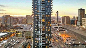 Un edificio de gran altura con múltiples balcones, rodeado por un paisaje urbano al atardecer.