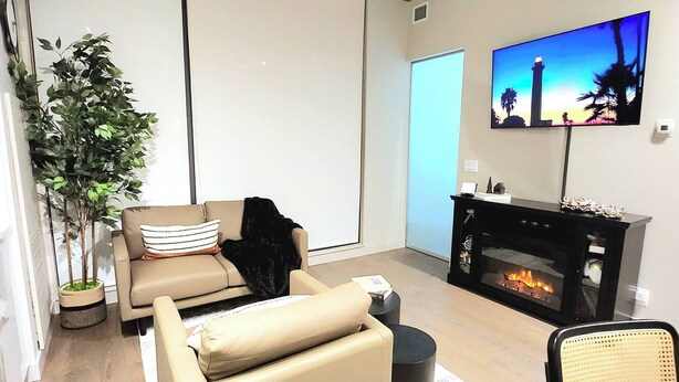 Una sala de estar moderna con un sofá, una mesita, una chimenea y un televisor montado en la pared.