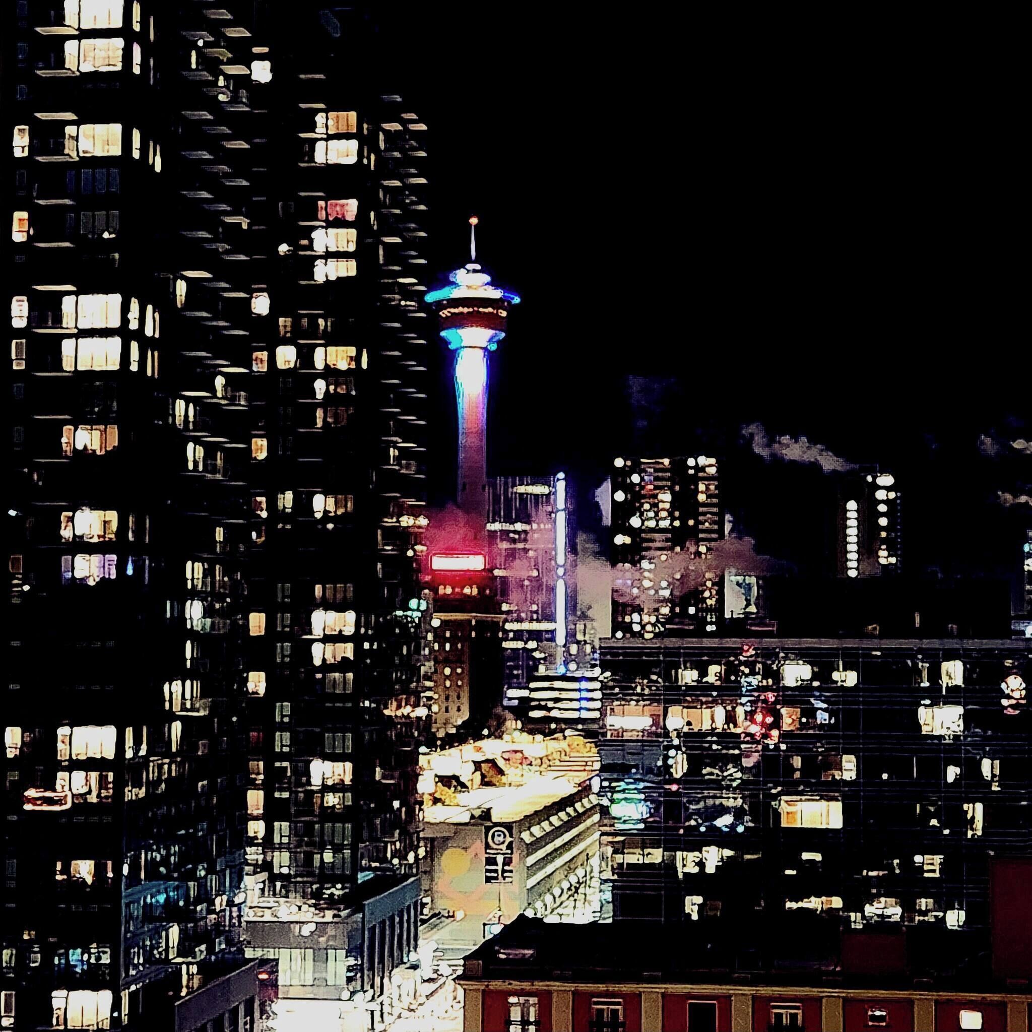 Un paisaje urbano nocturno con una torre destacada y edificios altos y numerosos.