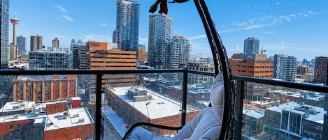 A hanging chair on a balcony with a cityscape view.
