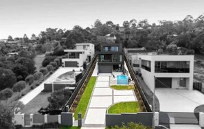 A modern building with a flat roof, a swimming pool, and a clear view of the surrounding landscape. - Elèvè | Luxury in Mount Martha with Gas Heated Pool & Bay Views (Mount Martha)