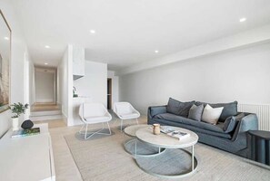 A modern living room with a grey sofa, white chairs, and a coffee table. - Elèvè | Luxury in Mount Martha with Gas Heated Pool & Bay Views (Mount Martha)