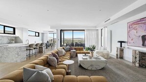 Ein modernes Wohnzimmer mit einer Couch, einem Couchtisch und Blick ins Freie.