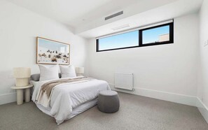 A modern bedroom with a bed, a window, a radiator, and a picture on the wall. - Elèvè | Luxury in Mount Martha with Gas Heated Pool & Bay Views (Mount Martha)