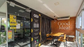 A modern interior with a glass door entrance, a black sign with QR codes, and a 'Good Idea!' sign on the wall. - Studio in Condo w/ Pool in POA Pue0308 (Porto Alegre)