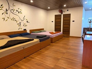 A room with two wooden beds, a wooden ceiling, and a wall with a tree mural. - Vagadrops (Peermade)