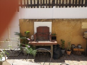 A patio area with a grill, potted plants, and a metal chair. - La Parenthèse d'Honfleur ~ 4 Bedrooms & Private Courtyard (La Rivière-Saint-Sauveur)