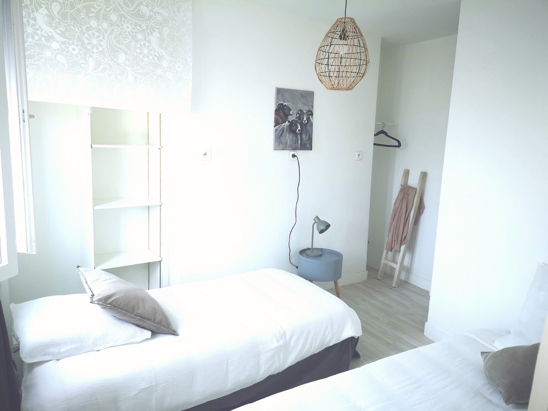A bedroom with a bed, bedside table, lamp, and a hanging light fixture.