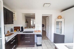 A compact kitchen with a central island, dark cabinetry, a coffee machine, and a trash bin. - La Parenthèse d'Honfleur ~ 4 Bedrooms & Private Courtyard (La Rivière-Saint-Sauveur)