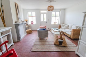 A spacious living room with a fireplace, a sofa set, a coffee table, and a large window providing natural light.