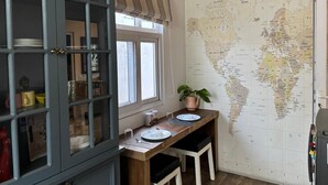 A kitchen with a wooden table, two chairs, a world map on the wall, and a cabinet with glass doors.