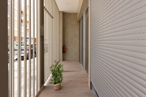 A corridor with a potted plant, a fire extinguisher, and a closed shutter door. - Brand-new apartment with an accessible bathroom and kitchen. Perfect for families! (Nerja)