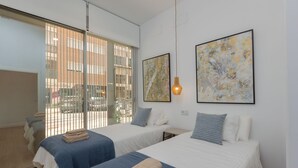 A hotel room with two beds, a large window with blinds, and two abstract paintings on the wall. - Brand-new apartment with an accessible bathroom and kitchen. Perfect for families! (Nerja)