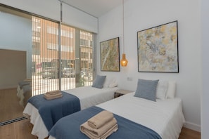 A hotel room with two beds, a large window with blinds, and two abstract paintings on the wall. - Brand-new apartment with an accessible bathroom and kitchen. Perfect for families! (Nerja)