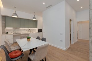 A modern kitchen with marble countertops, pendant lighting, and a dining area with a marble table and chairs. - Brand-new apartment with an accessible bathroom and kitchen. Perfect for families! (Nerja)