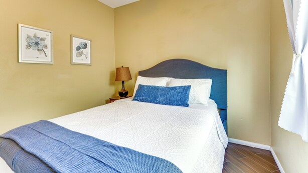 A bedroom with a bed, a nightstand, a lamp, and two framed botanical prints on the wall. - Pool & Hot Tub Access! Oceanside Escape Near Golf (Oceanside)