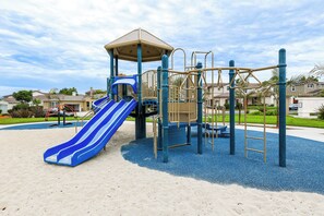 Ein Spielplatz mit Rutsche, Klettergerüsten und einem überdachten Spielbereich.