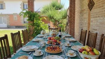 An outdoor dining table set with plates, glasses, and a fruit bowl.