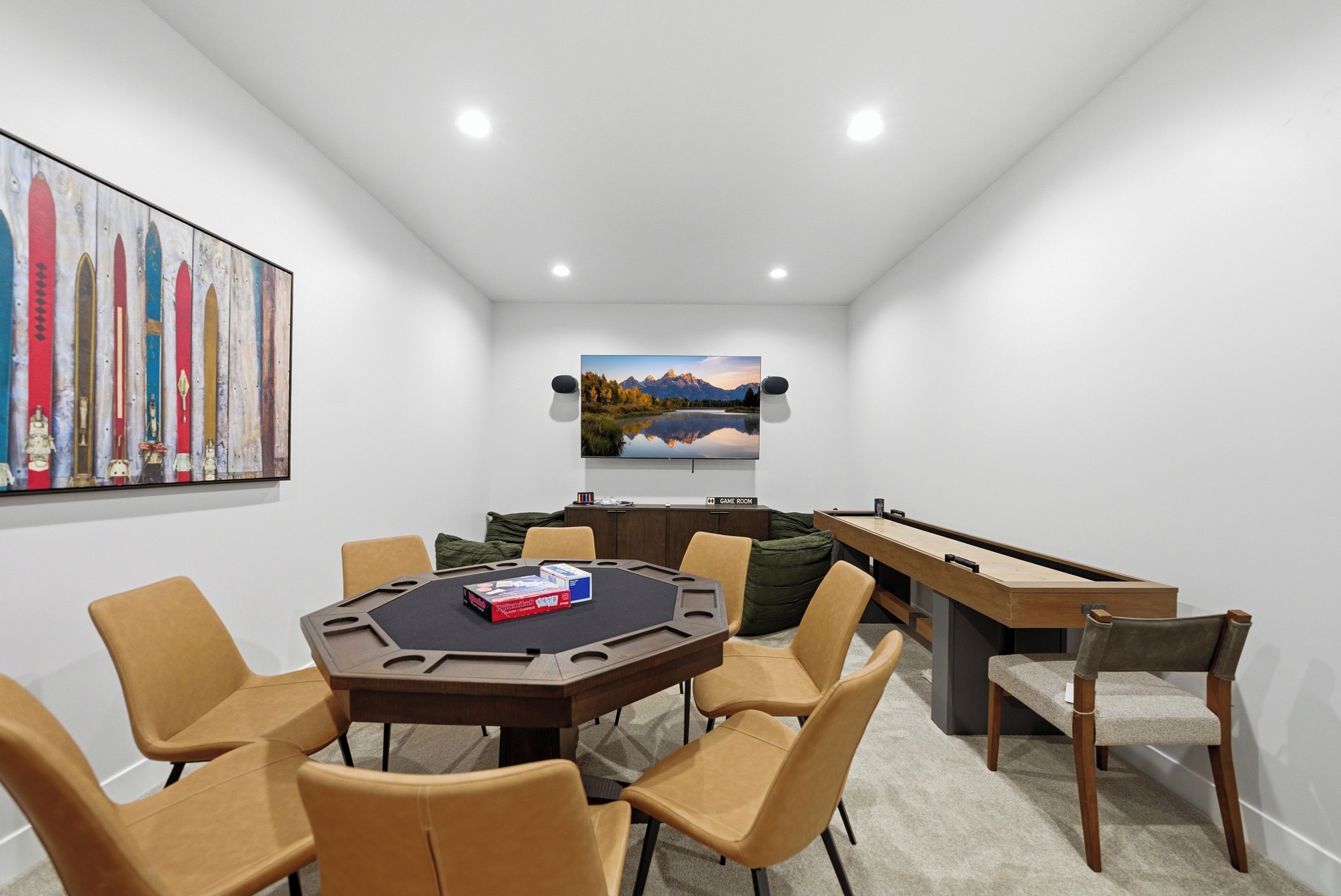 Ein Zimmer mit einem runden Tisch, Stühlen, einem Billardtisch, einem Gemälde und einem Fernseher an der Wand.