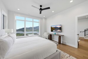 Ein Schlafzimmer mit einem großen Bett, Seeblick und Deckenventilator.
