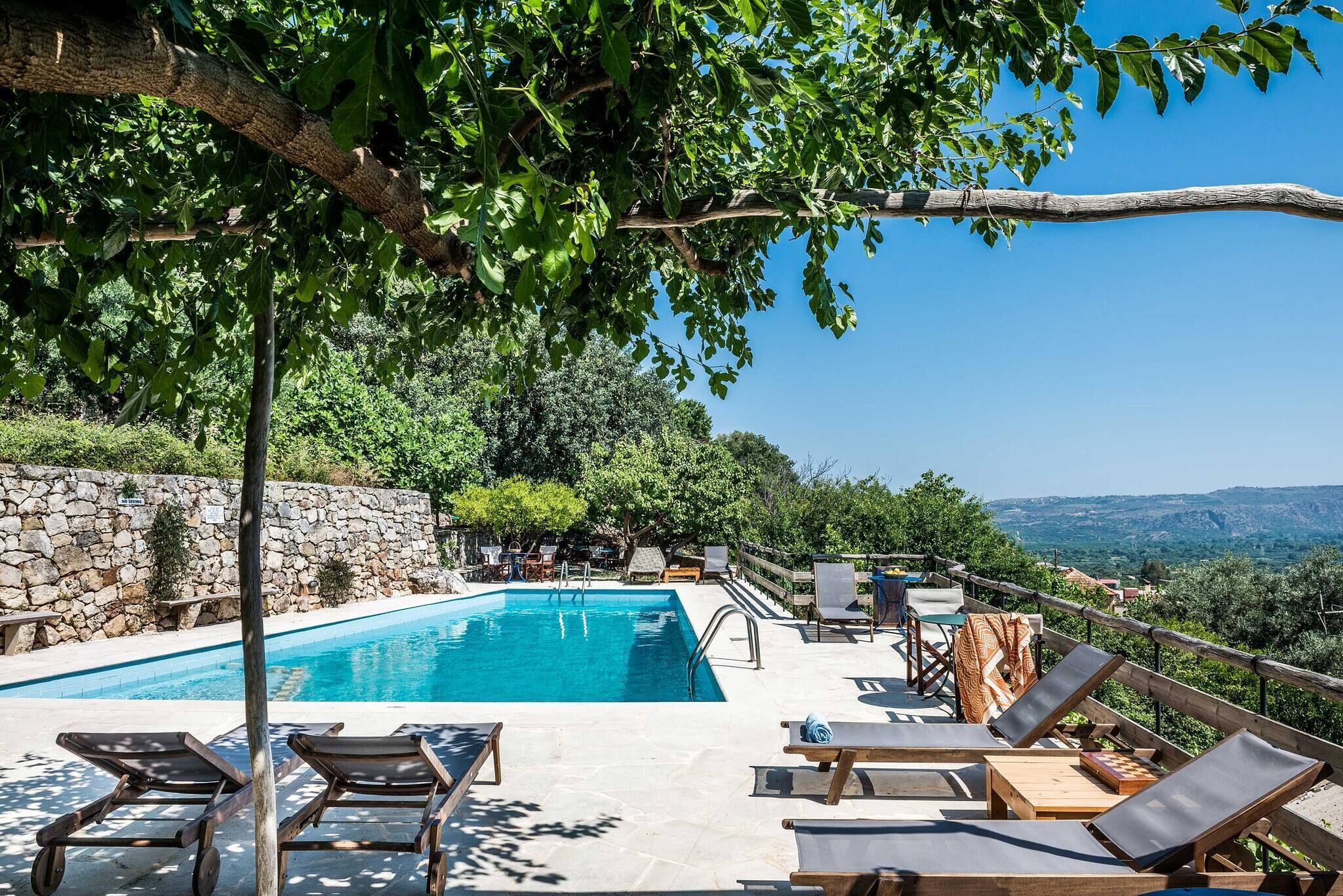 A pool area with lounge chairs and a stone wall.