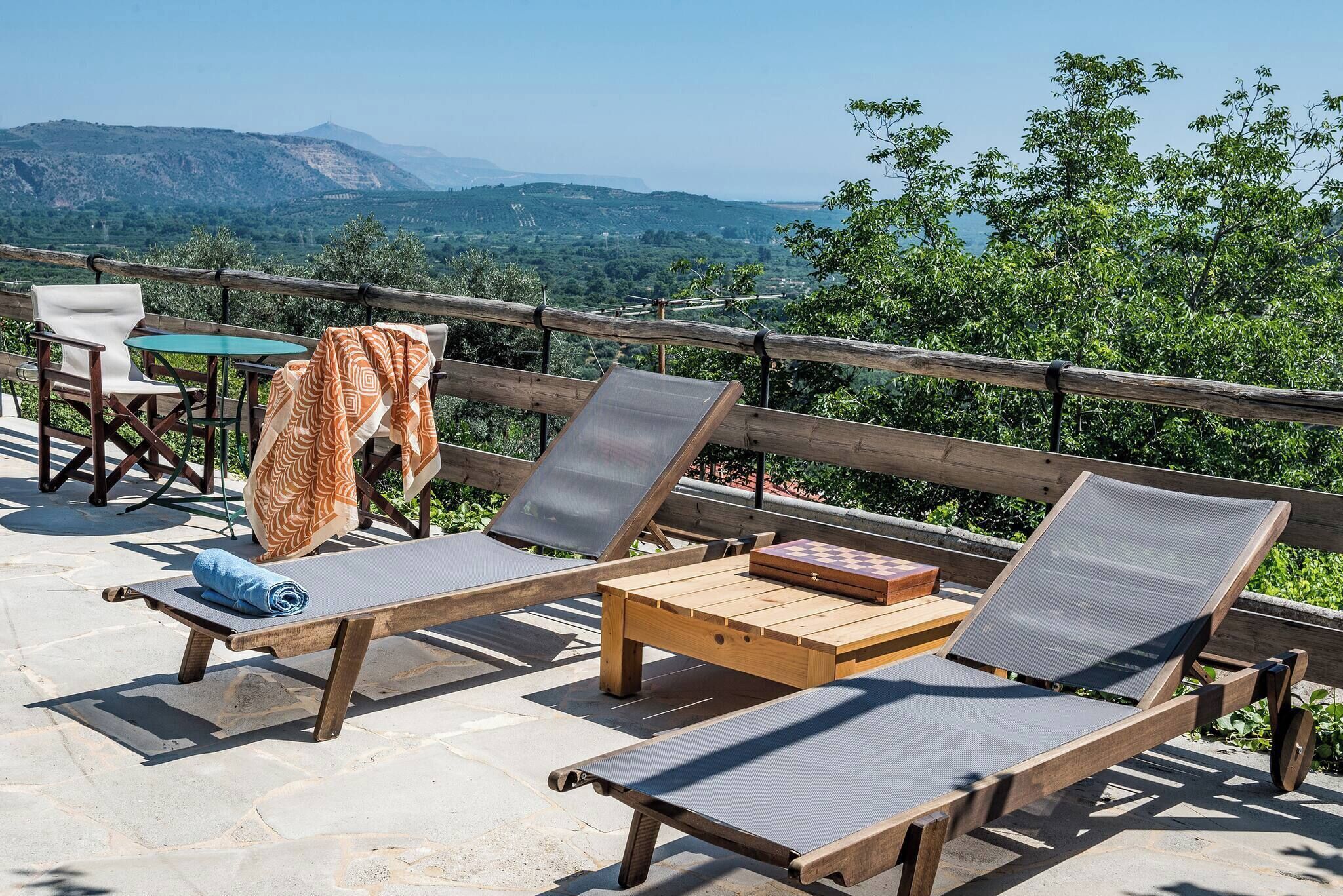 A terrace with wooden lounge chairs, a table, and a chessboard.