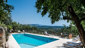 Ein rechteckiger Pool mit Holzterrasse, umgeben von Liegestühlen und einem Holzzaun.