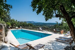 A rectangular pool with a wooden deck, surrounded by lounge chairs and a wooden fence. - Kamares – a restaured Venetian domain retreat (Macheri)