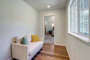 A hallway with a white sofa, a window, and a door leading to another room. - Riffle Road Ranch: 10 Acres, 8 Mi to Silverwood (Spirit Lake)