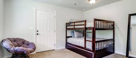 A room with a bunk bed, a chair, and a door.