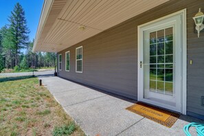 A house with a covered porch, a welcome mat, and a hose on the ground. - Riffle Road Ranch: 10 Acres, 8 Mi to Silverwood (Spirit Lake)