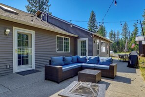 A residential property with a covered patio area featuring a sectional sofa and a fire pit. - Riffle Road Ranch: 10 Acres, 8 Mi to Silverwood (Spirit Lake)