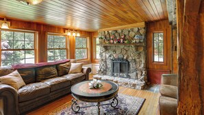 A cozy cabin interior with a stone fireplace, leather sofa, and wooden ceiling. - On Horse Farm! Home w/ Pond Access in Spring Creek (Spring Creek)