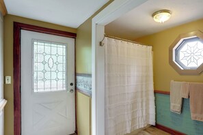 A bathroom with a white door, a window with a geometric pattern, a shower curtain, and a towel rack with towels. - On Horse Farm! Home w/ Pond Access in Spring Creek (Spring Creek)