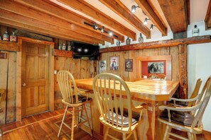 Un interior de madera con una zona de bar, sillas de madera y una puerta de madera.