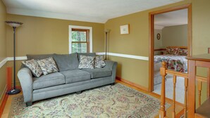 A room with a grey sofa, a patterned rug, a wooden chair, and a bed with a quilt. - On Horse Farm! Home w/ Pond Access in Spring Creek (Spring Creek)