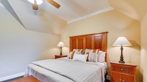 A hotel room with a large bed, two bedside tables with lamps, a wooden bench, and a ceiling fan. - Pool Access + Golf View: 5BR Springfield Home (Springfield)
