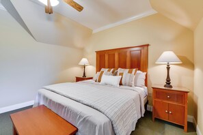 A hotel room with a large bed, two bedside tables with lamps, a wooden bench, and a ceiling fan. - Pool Access + Golf View: 5BR Springfield Home (Springfield)
