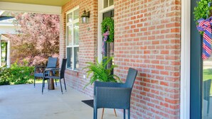 A brick building with a porch, two wicker chairs, and a potted plant. - Pool Access + Golf View: 5BR Springfield Home (Springfield)