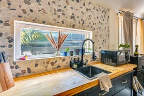 Eine Küche mit Steinwand, einem Fenster mit Ausblick, einem Spülbecken, einer Mikrowelle und einem Schrank.