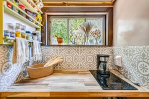 A kitchen with a coffee maker, a window with a view of trees, and a shelf with various jars and containers. - Grill & Porch! Extended Escape, 2 Mi to Ybor City (Tampa)