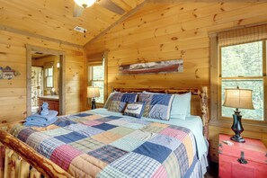 A wooden cabin bedroom with a bed, quilt, bedside table, lamp, and a red chest of drawers. - Blue Ridge Bliss: Peaceful Retreat w/ Deck (Blue Ridge)