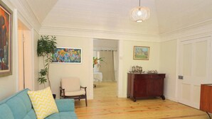 Een woonkamer met een blauwe bank, een houten kast en een schilderij aan de muur.
