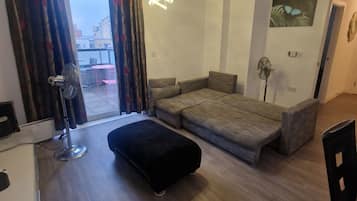 A modern living room with a sofa, ottoman, and a dining area with chairs.