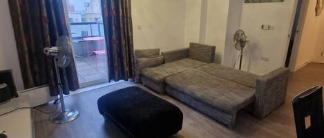 A modern living room with a sofa, ottoman, and a dining area with chairs.